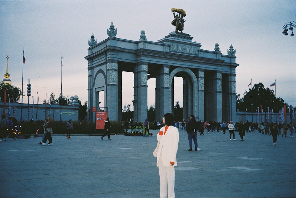 a man in a white suit standing in front of a monument