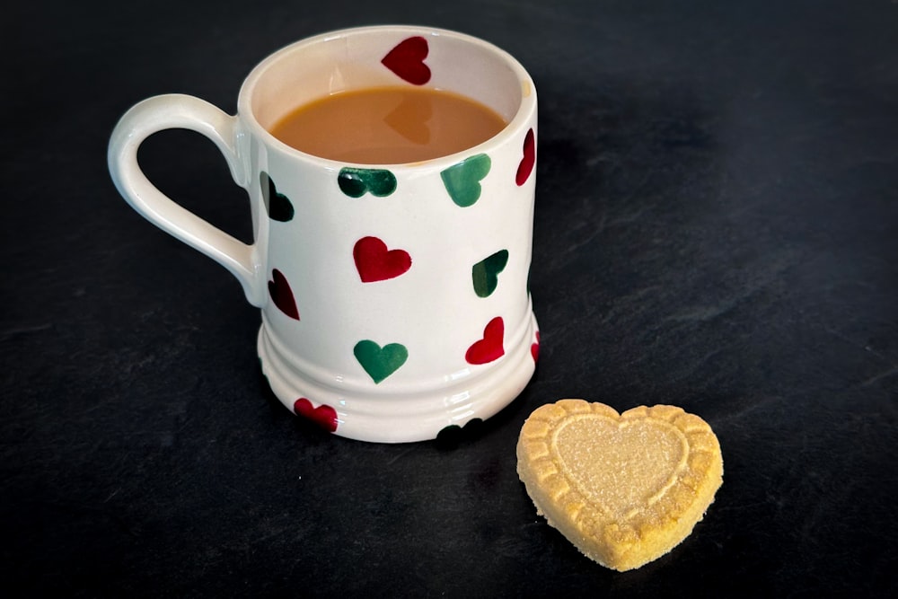 a heart shaped cookie next to a cup of tea