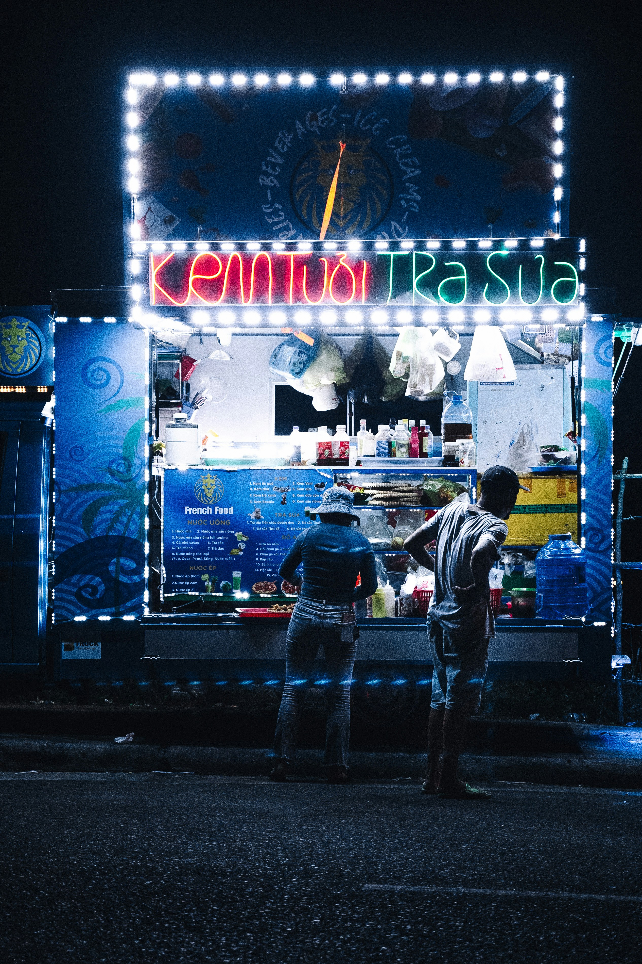 two people standing in front of a food truck