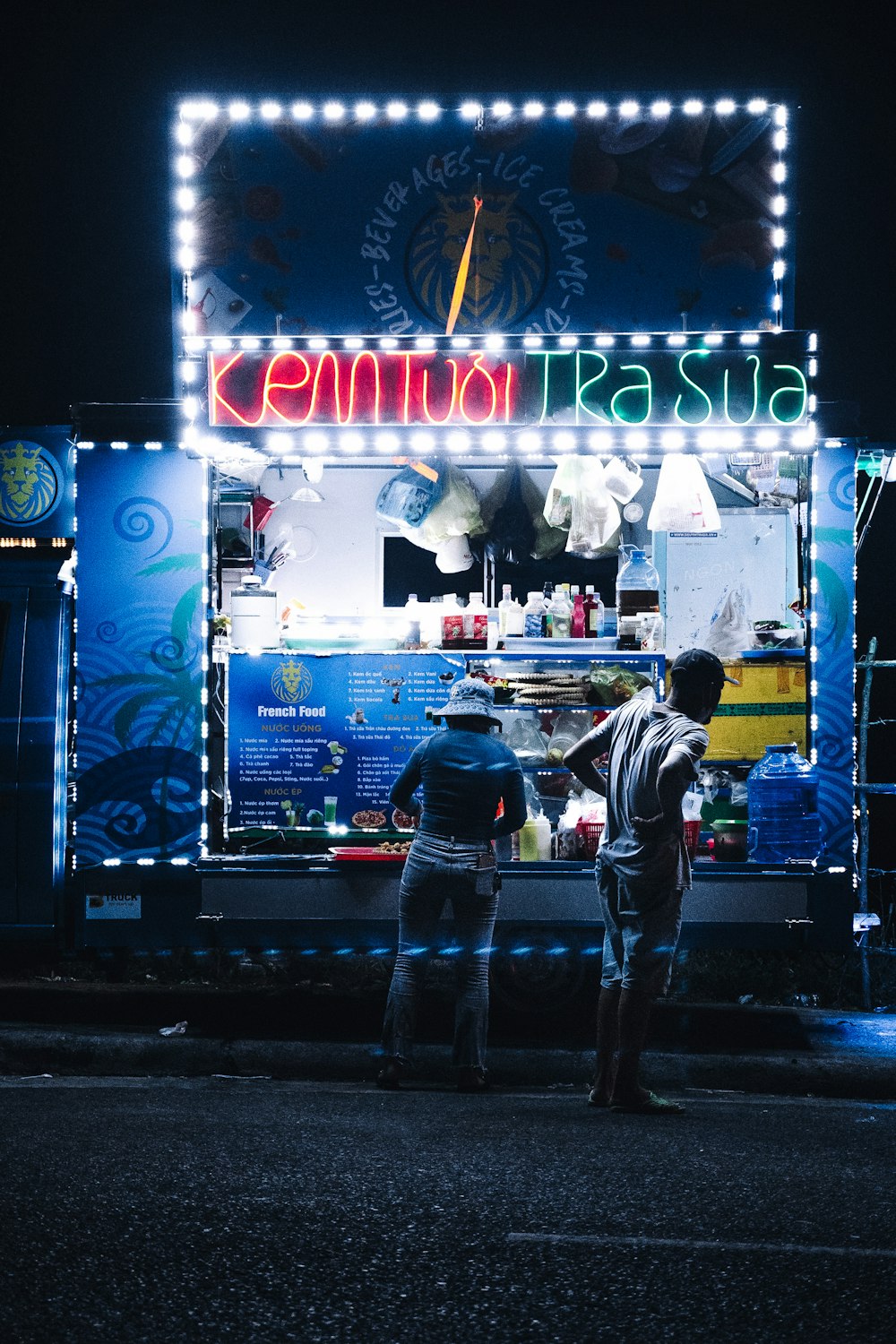 two people standing in front of a food truck