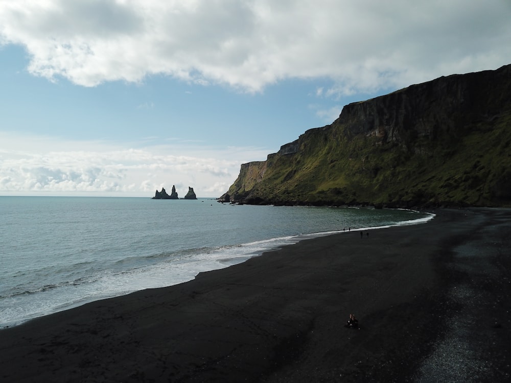 a black sand beach with cliffs in the background
