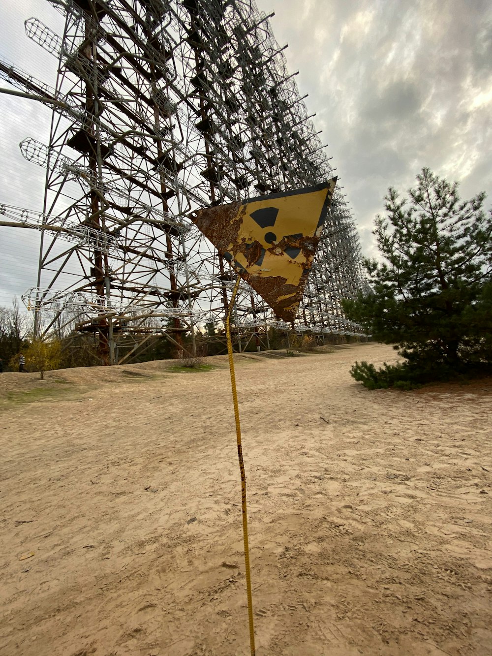 un letrero amarillo en forma de triángulo sentado en la parte superior de un campo de tierra