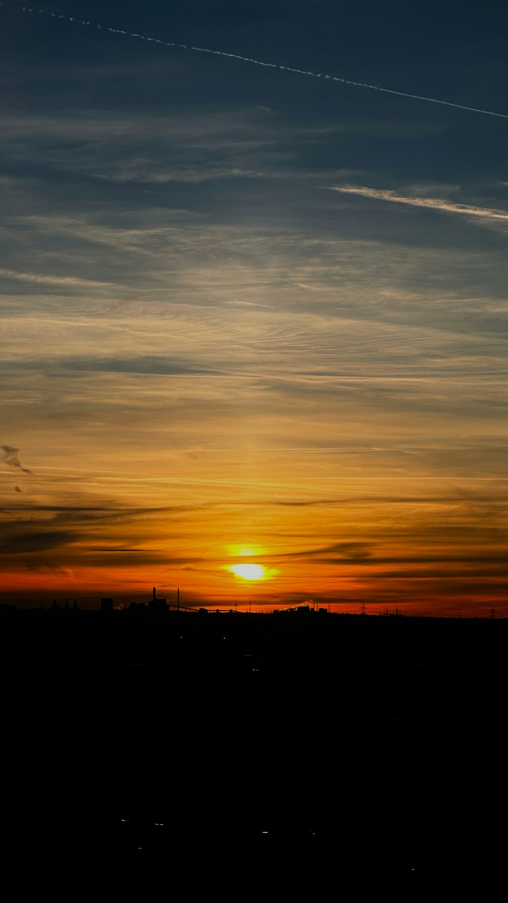 a plane flying in the sky at sunset