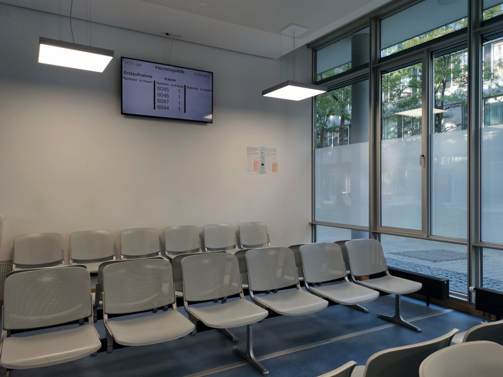 a row of white chairs sitting in front of a window