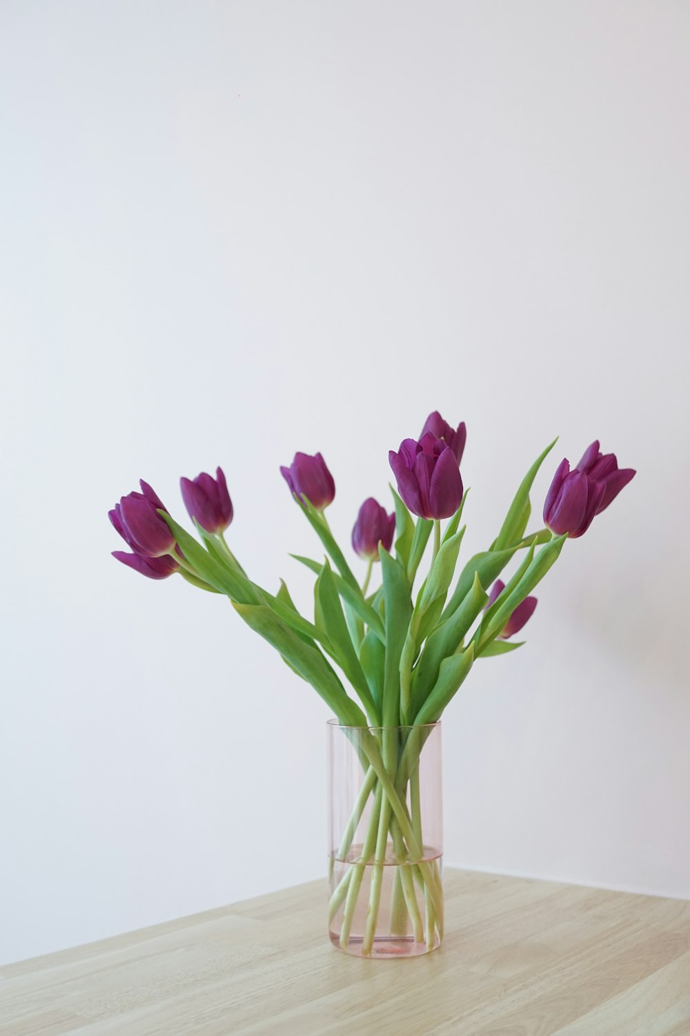 a vase filled with purple flowers on top of a wooden table