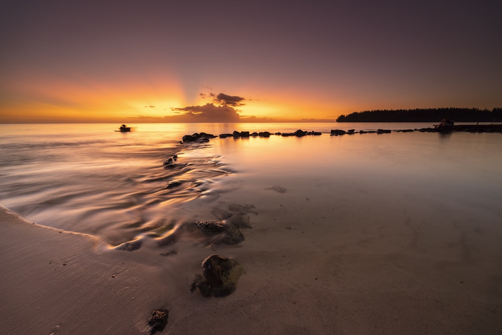 the sun is setting over the water at the beach