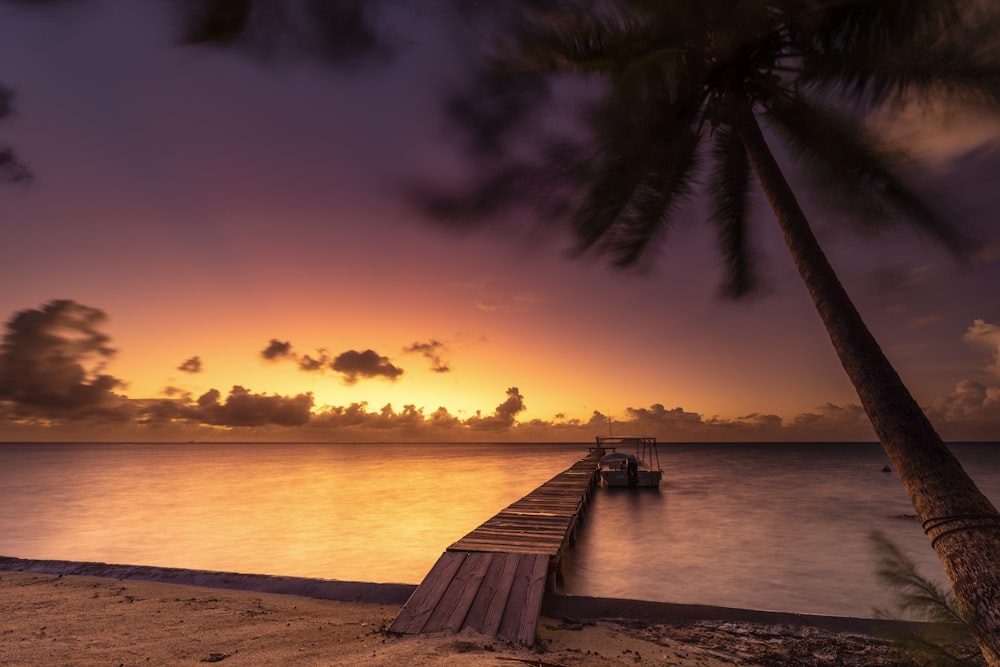 a dock on a beach with a sunset in the background