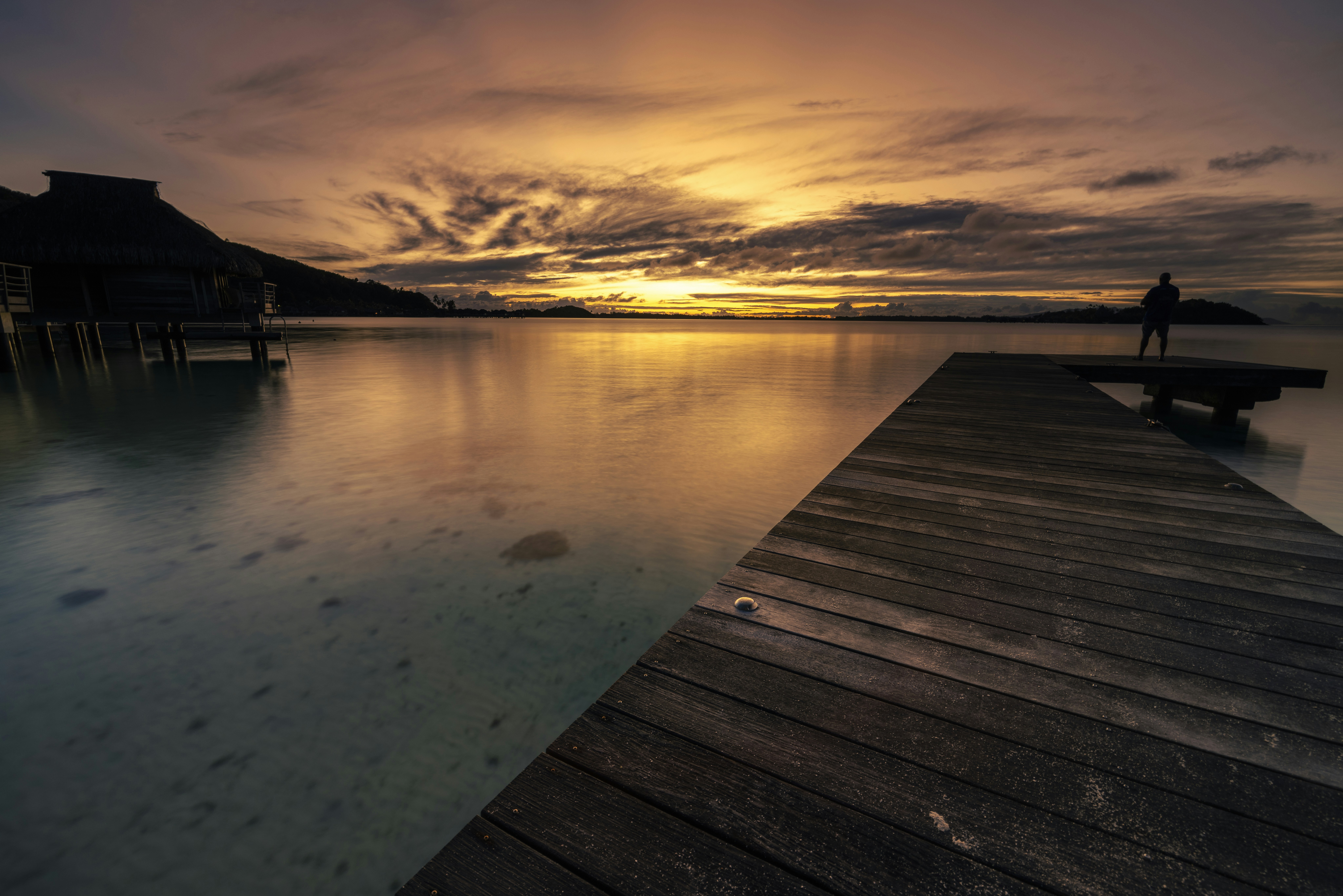a person standing on a dock at sunset, 