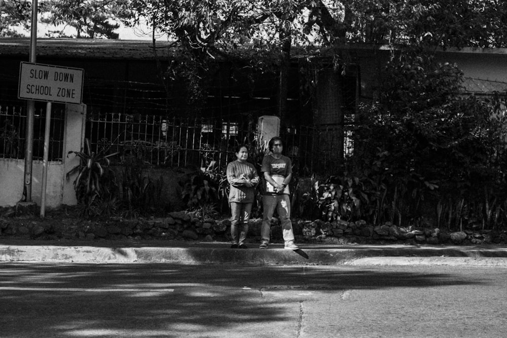 a black and white photo of two people sitting on a bench