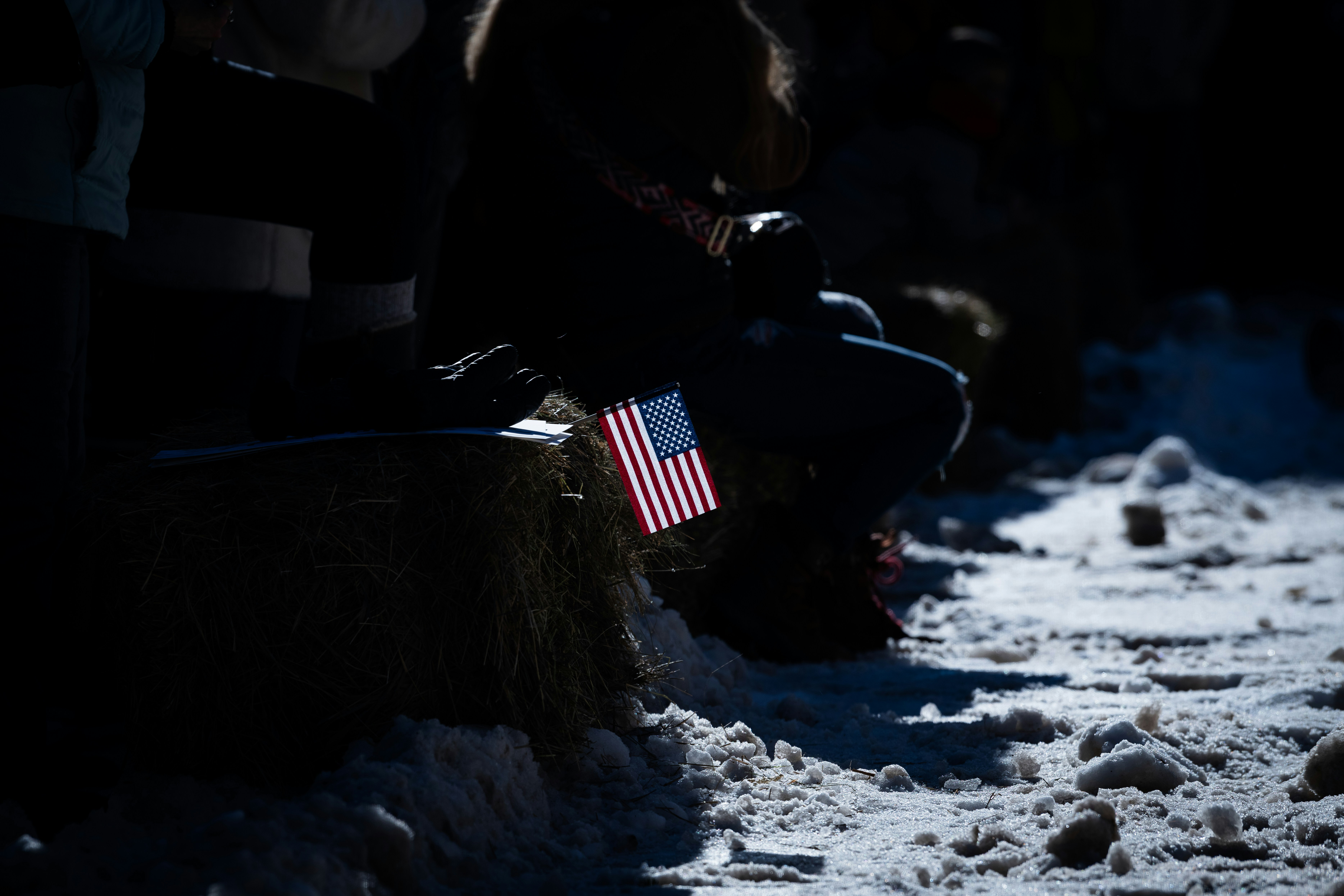 a person sitting in the snow with an american flag on their lap