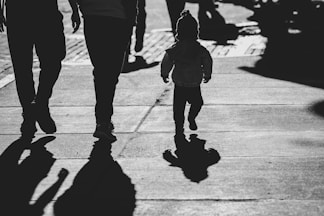 a black and white photo of a little girl walking with her parents