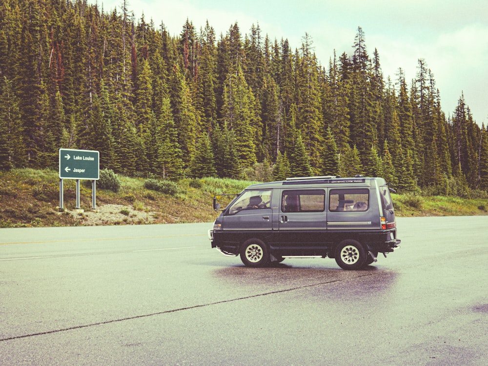 a van driving down a road next to a forest