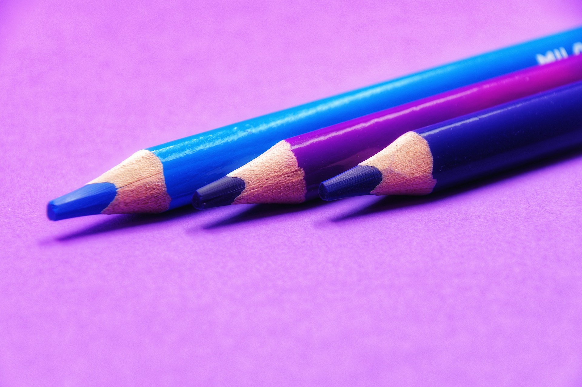 two pencils are sitting side by side on a purple surface