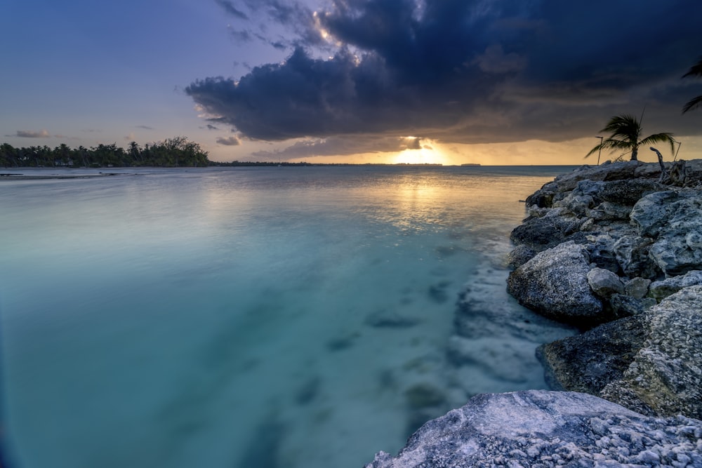 the sun is setting over the ocean with palm trees