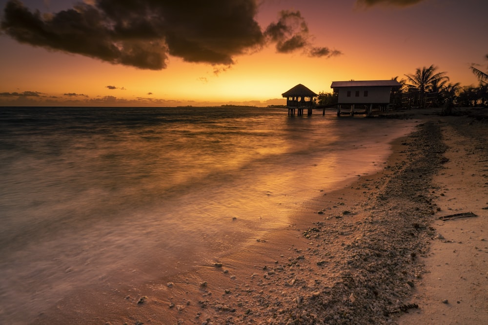 the sun is setting over the water at the beach