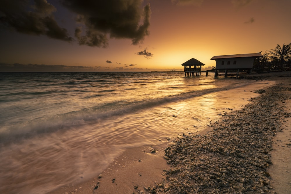 the sun is setting over the water at the beach