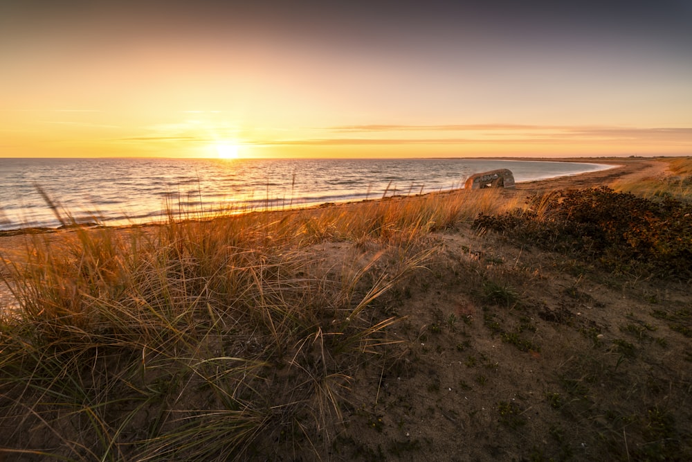 the sun is setting over the ocean on the beach