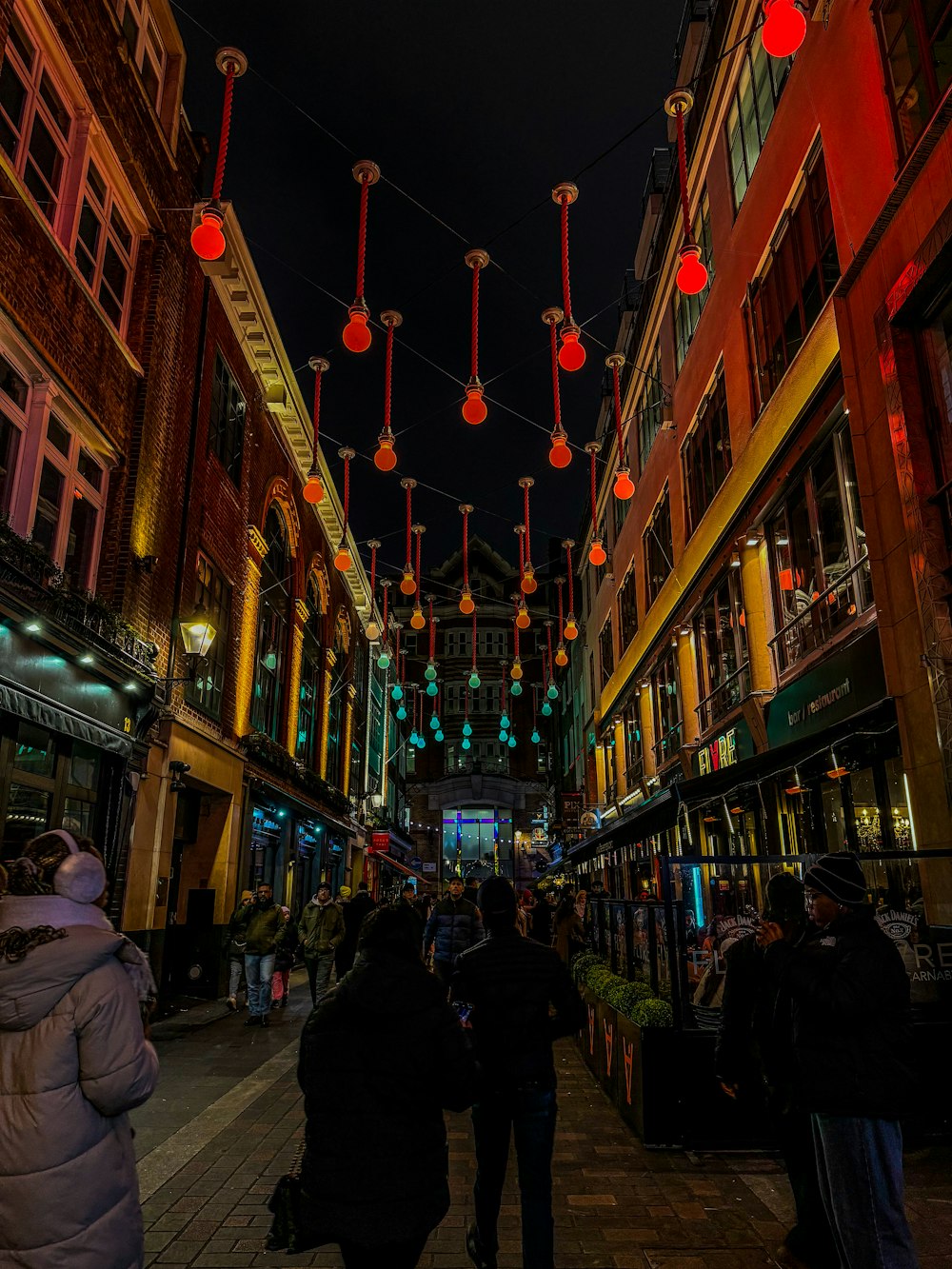 a group of people walking down a street next to tall buildings