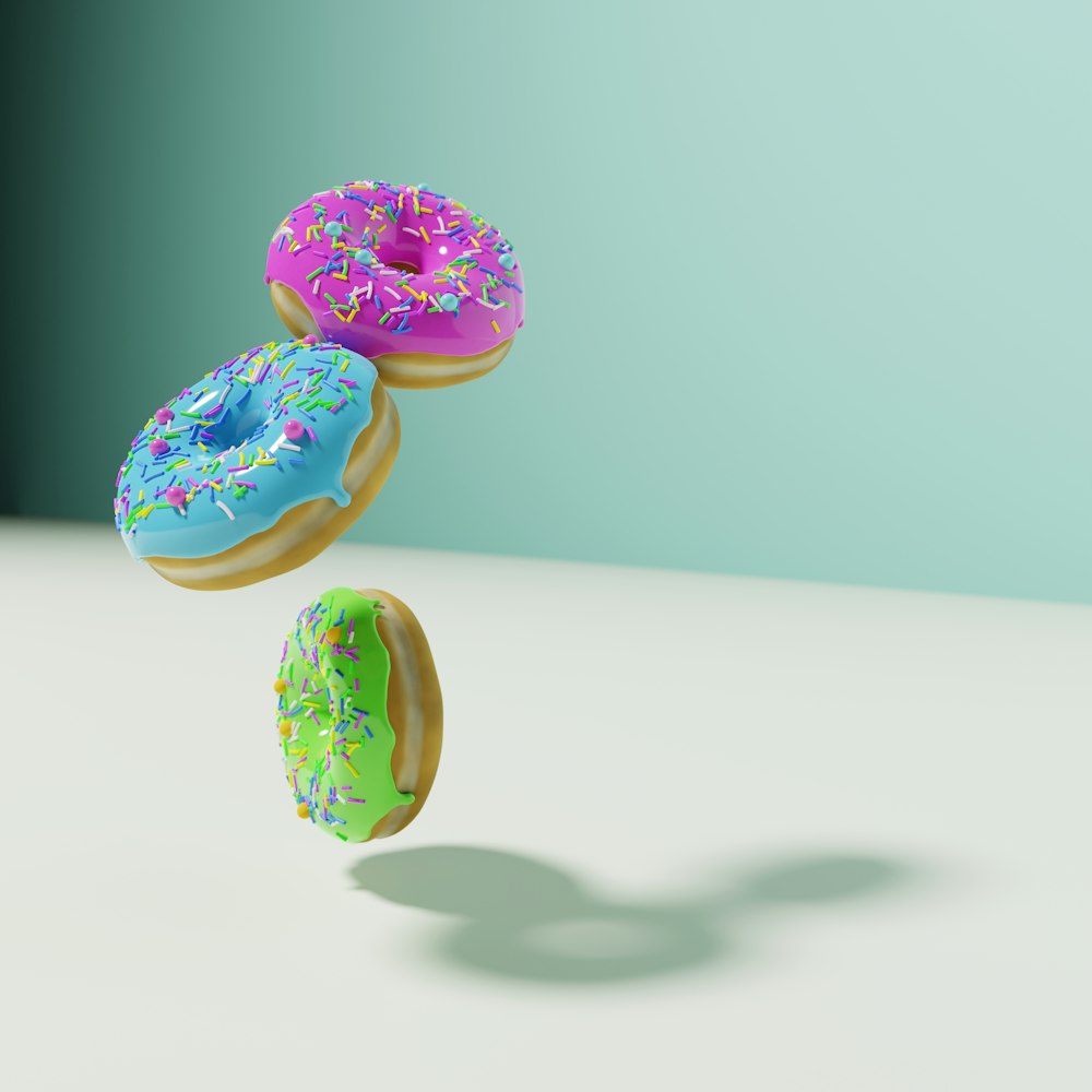 three donuts with sprinkles are flying in the air