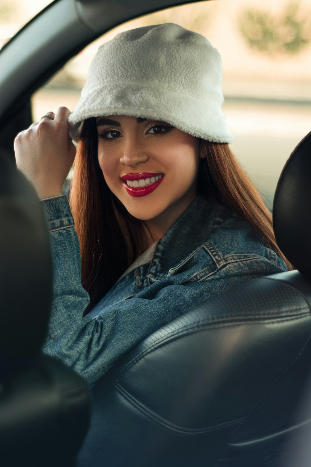 a woman sitting in a car wearing a hat