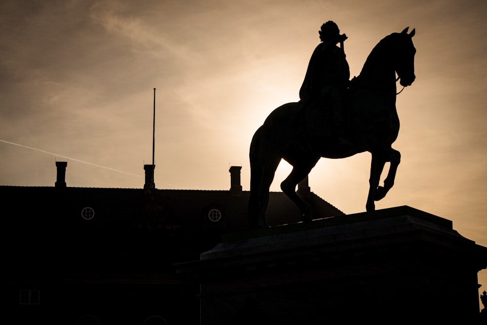 uma silhueta de uma estátua de um homem montado em um cavalo
