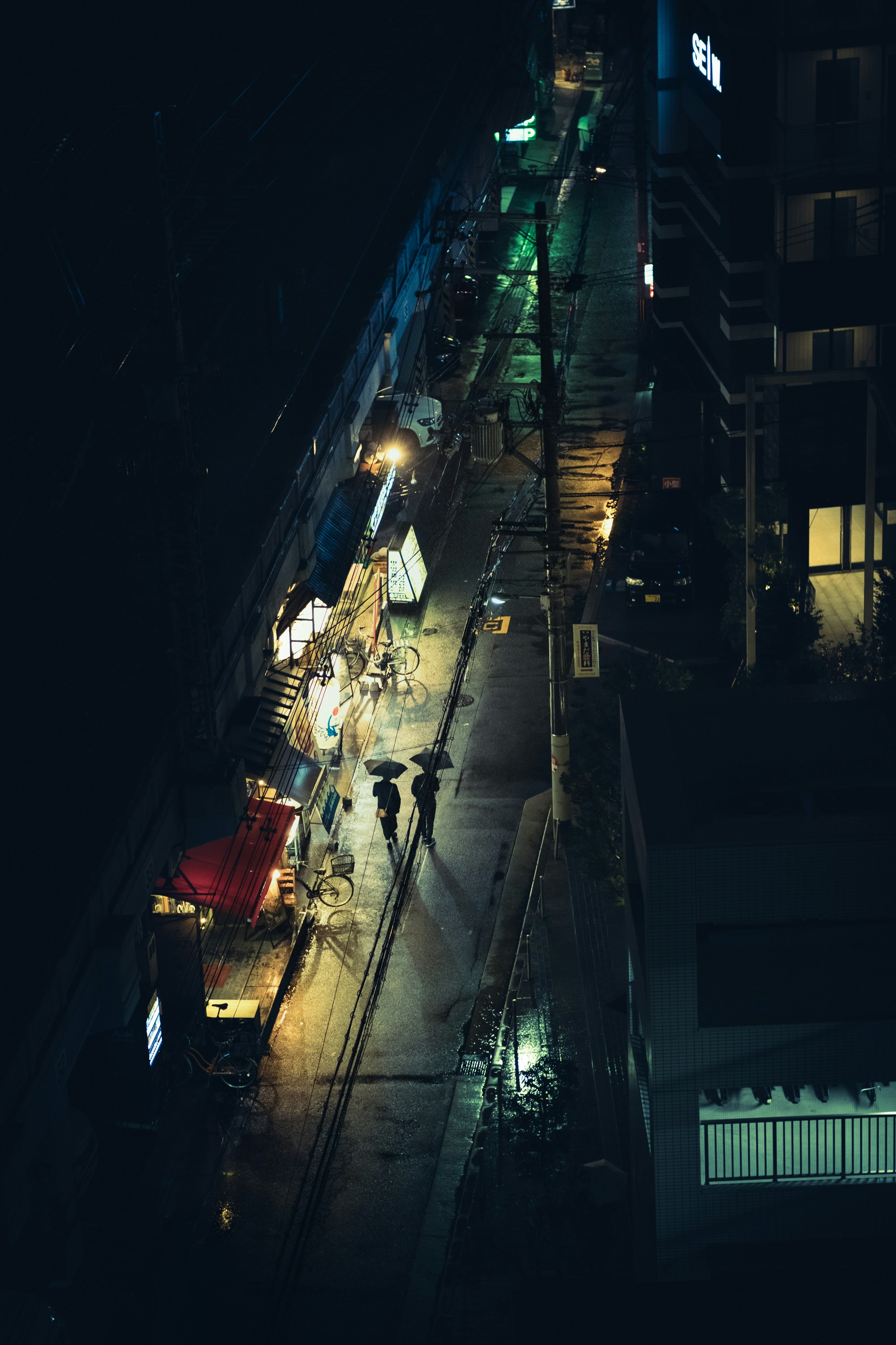 a city street at night with people walking on the sidewalk