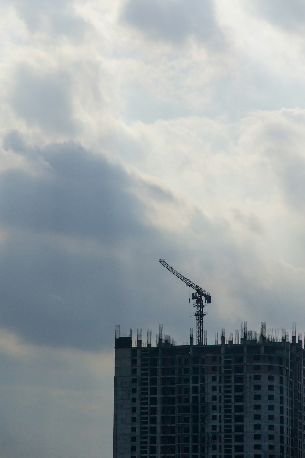 a crane on top of a tall building under a cloudy sky