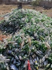 a pile of empty beer bottles sitting on top of a field