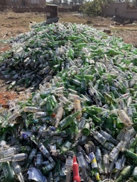 a pile of empty beer bottles sitting on top of a field