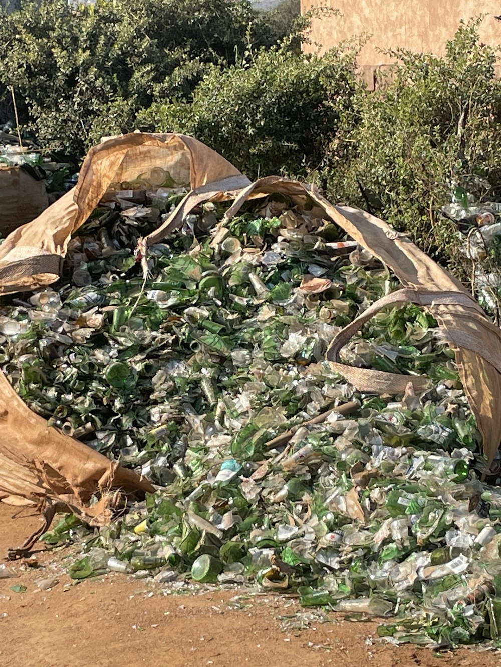 a pile of glass bottles sitting on top of a dirt field