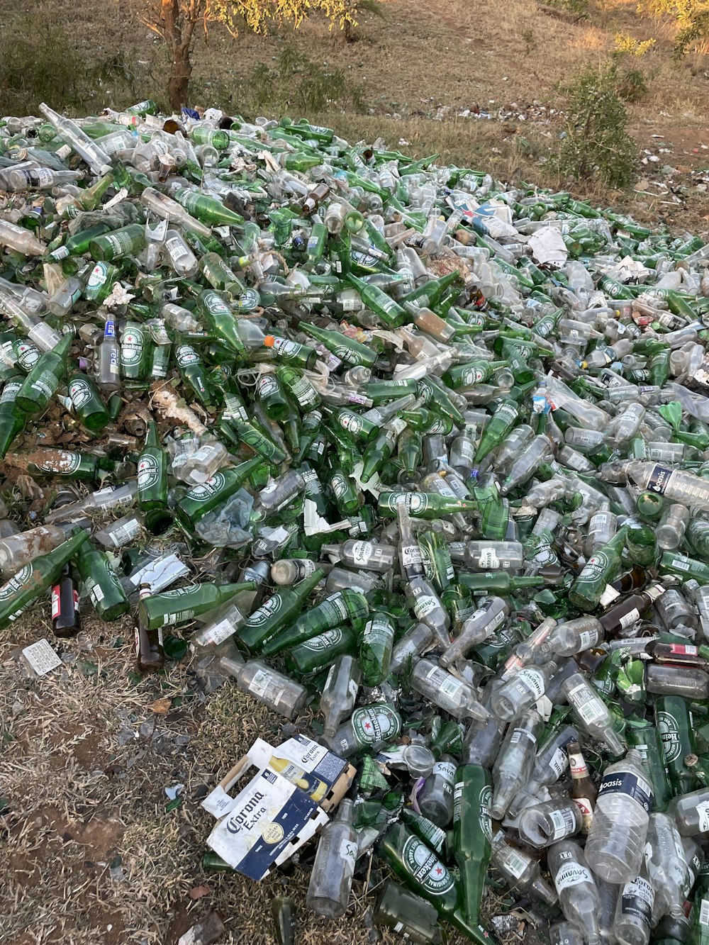 a pile of empty beer bottles sitting on top of a field