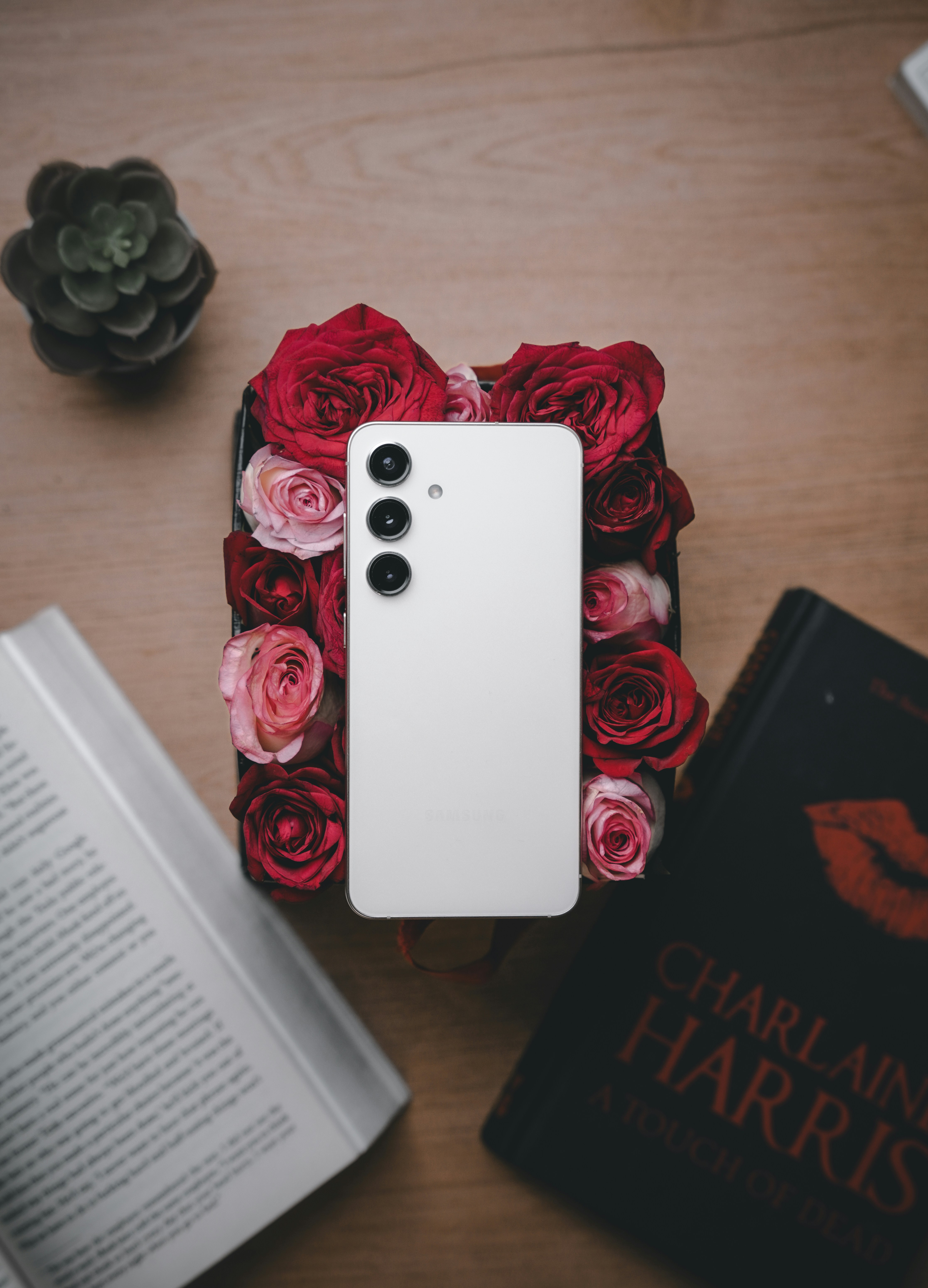 a white cell phone sitting on top of a table next to a book