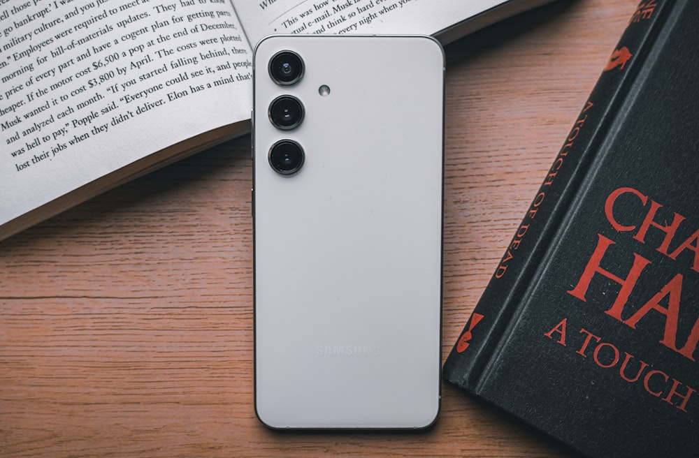 a cell phone sitting on top of a table next to a book