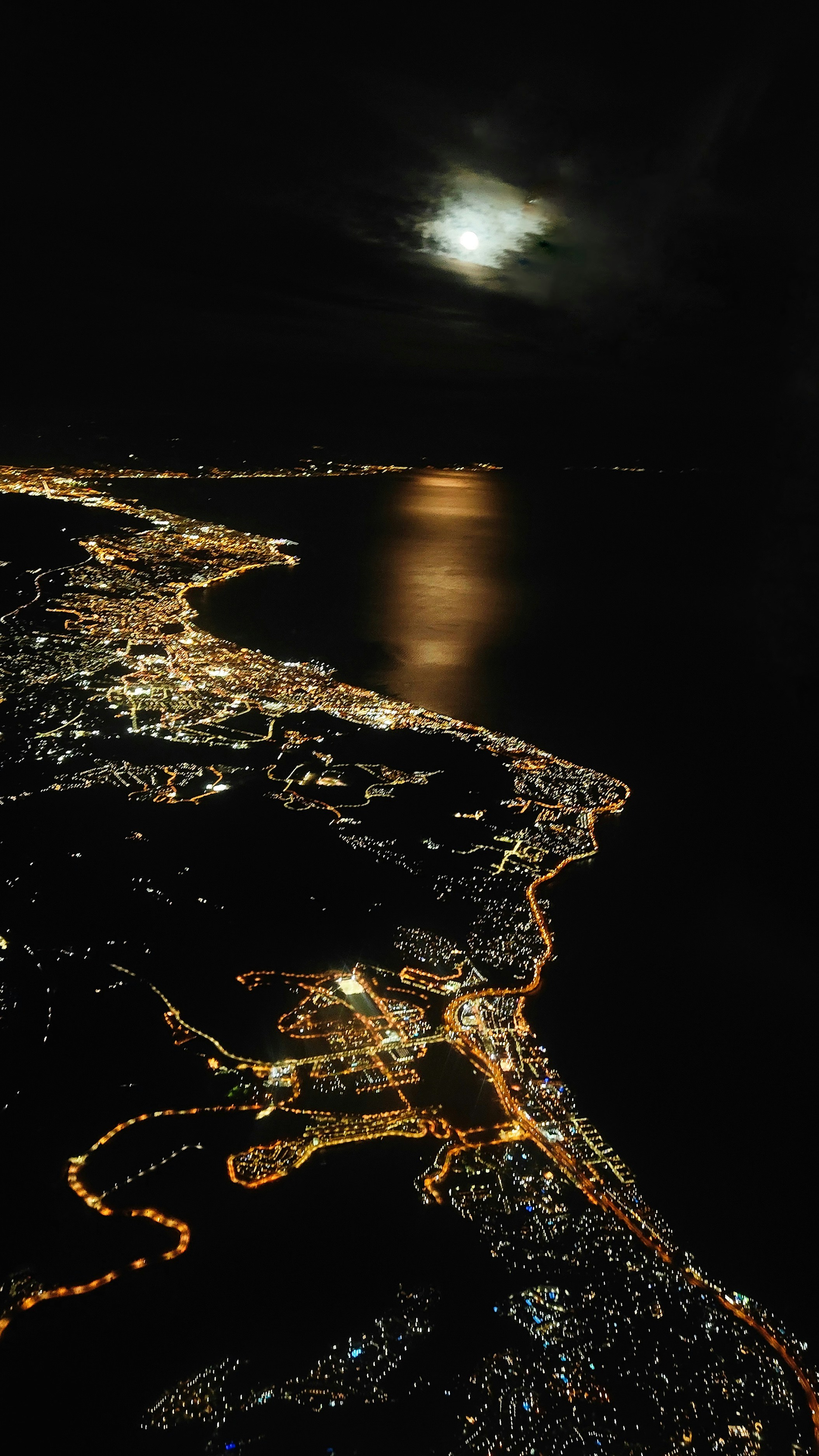 Mumbai aerial view at night with orange street lights and coastal city lights reflecting on water