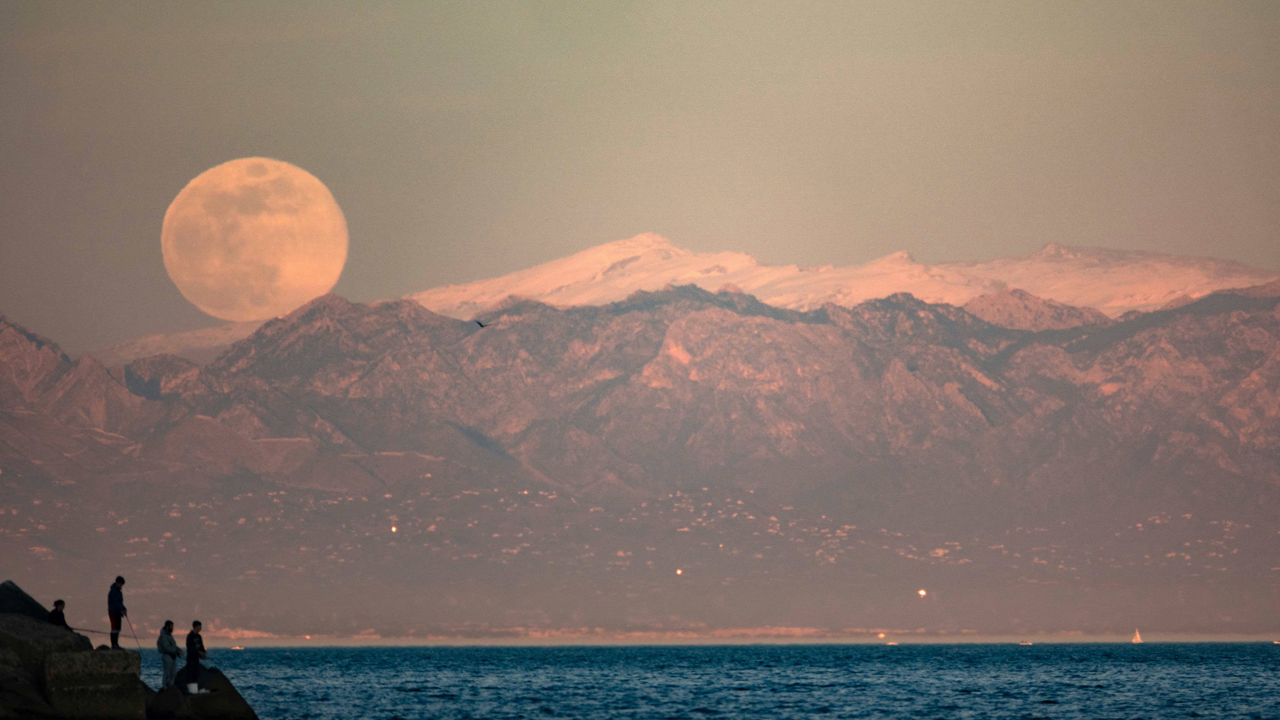 a couple of people standing on top of a rock next to a body of water