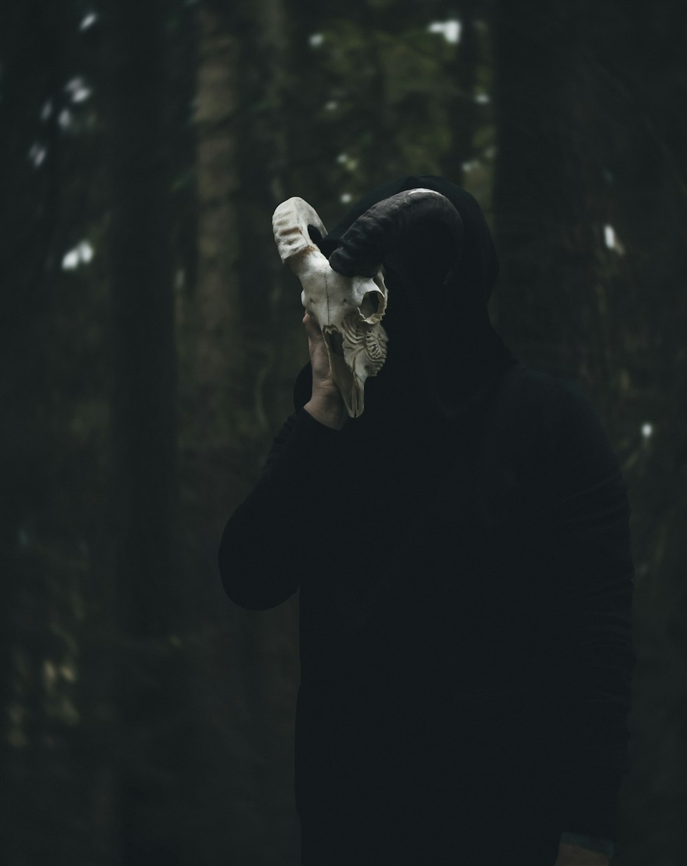 a man in a black hoodie holding a white mask