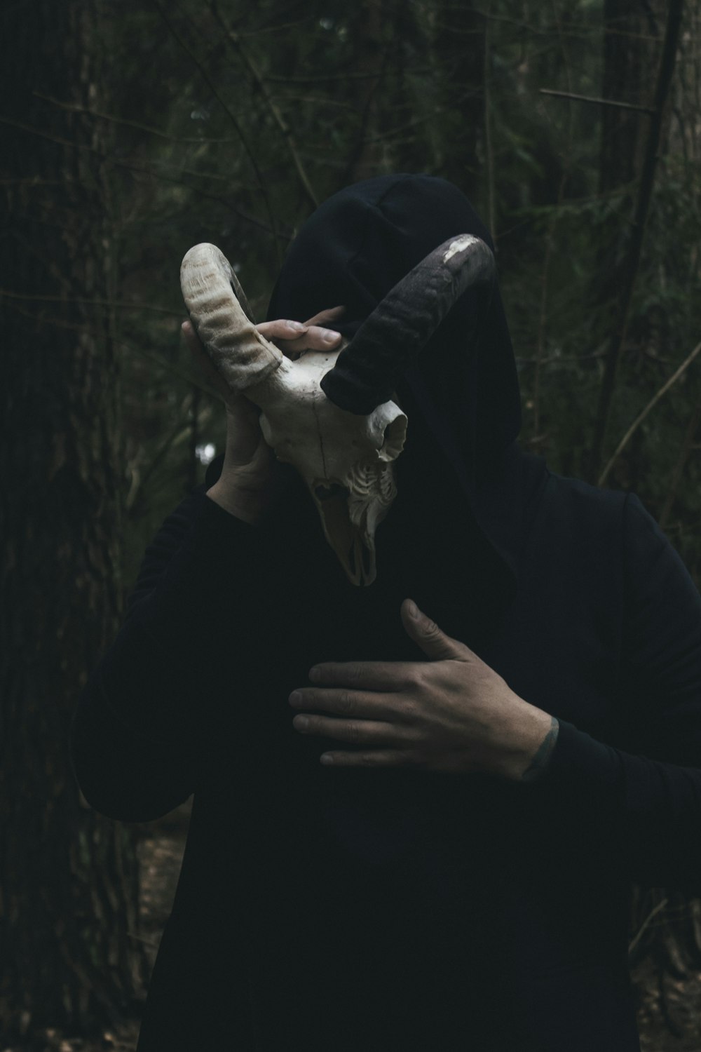 a person in a black hoodie holding a white object