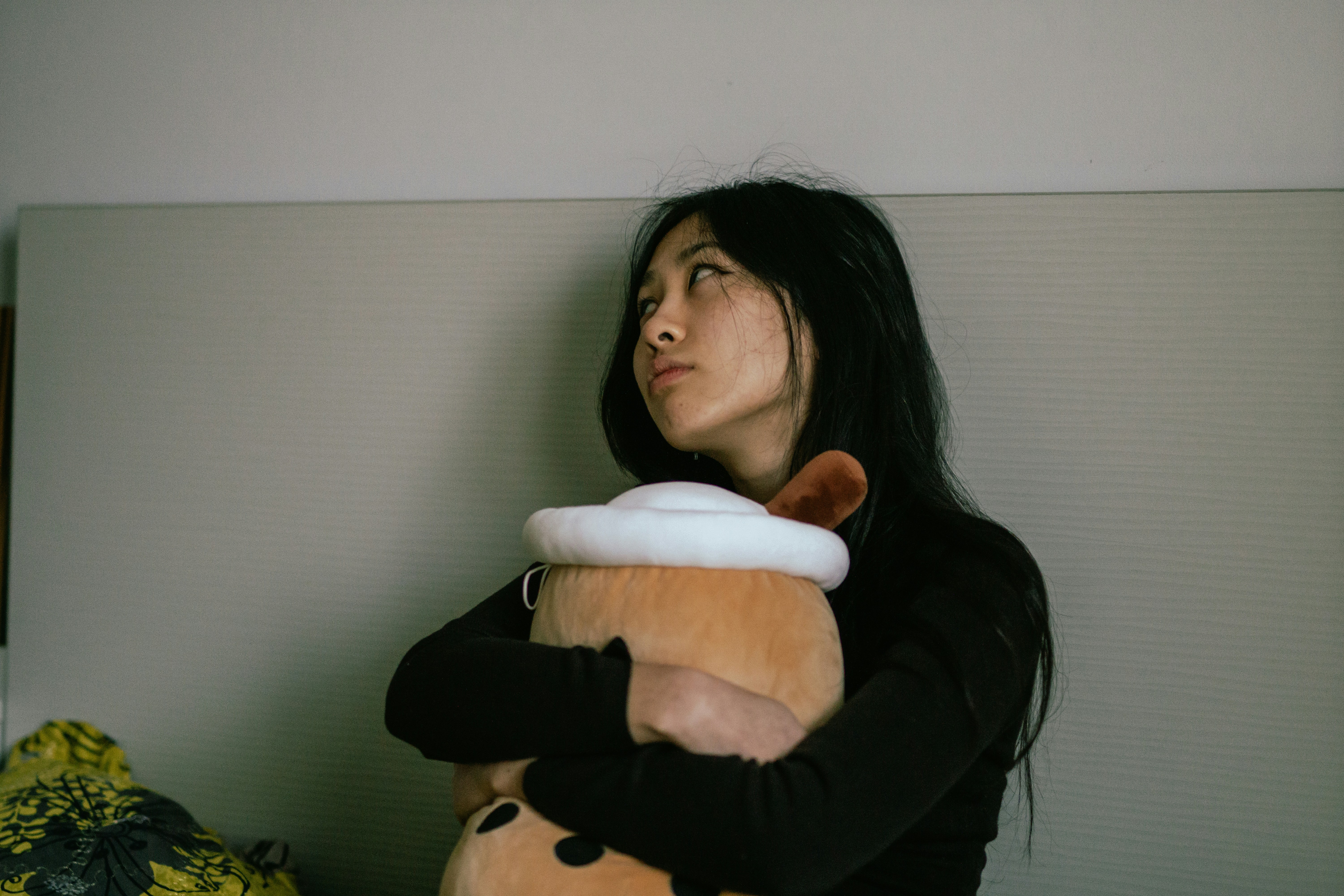 une femme assise sur un lit tenant un animal en peluche