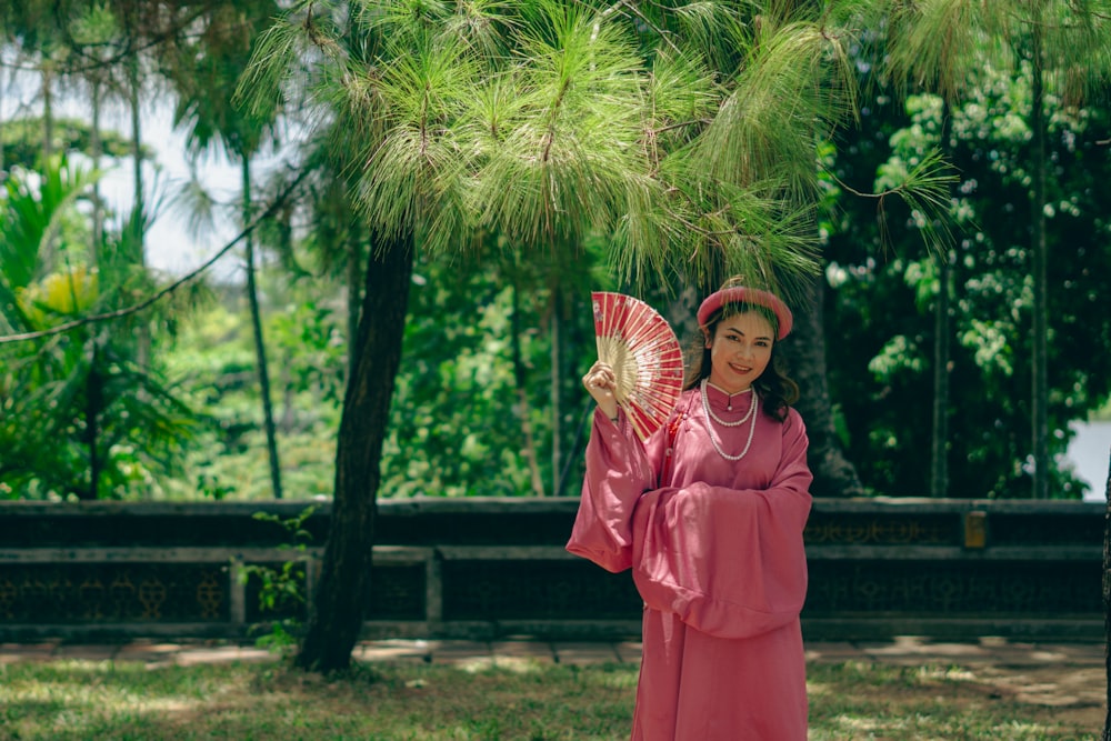 a woman in a pink dress is holding a fan