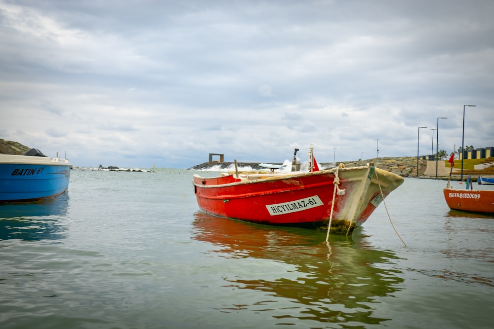 a red boat sitting in the middle of a body of water