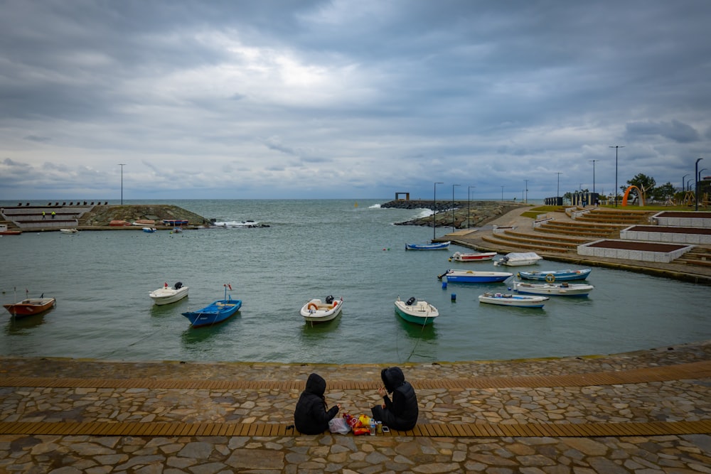 a couple of people sitting on the edge of a pier