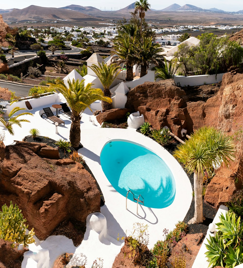 an aerial view of a pool surrounded by rocks and palm trees