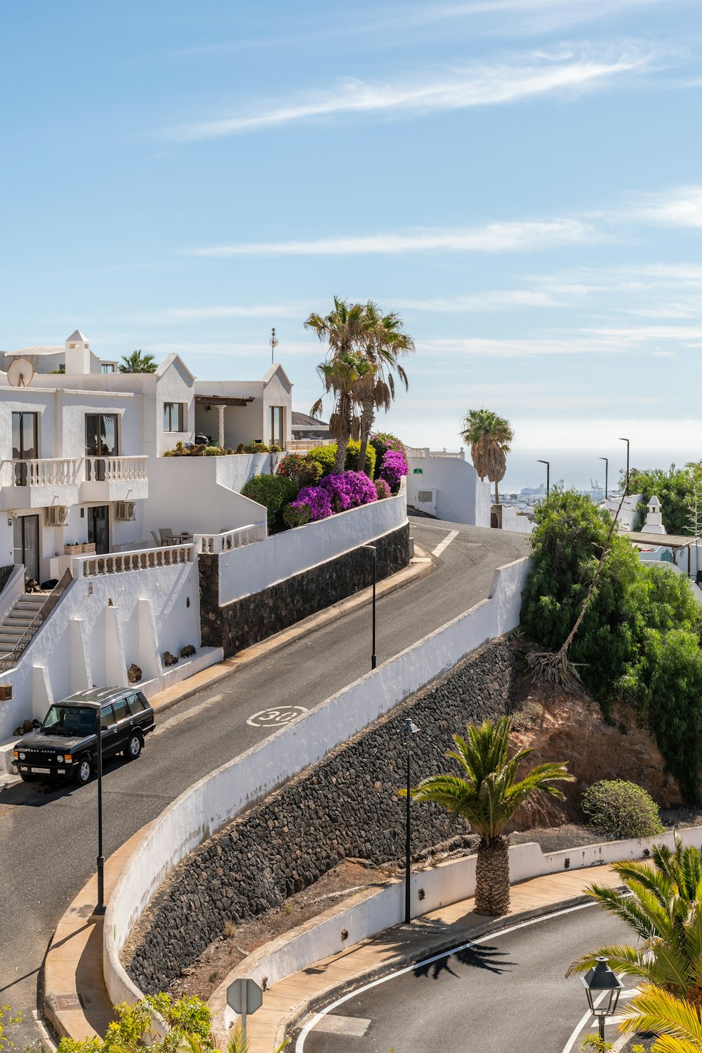 a black car driving down a street next to a hill