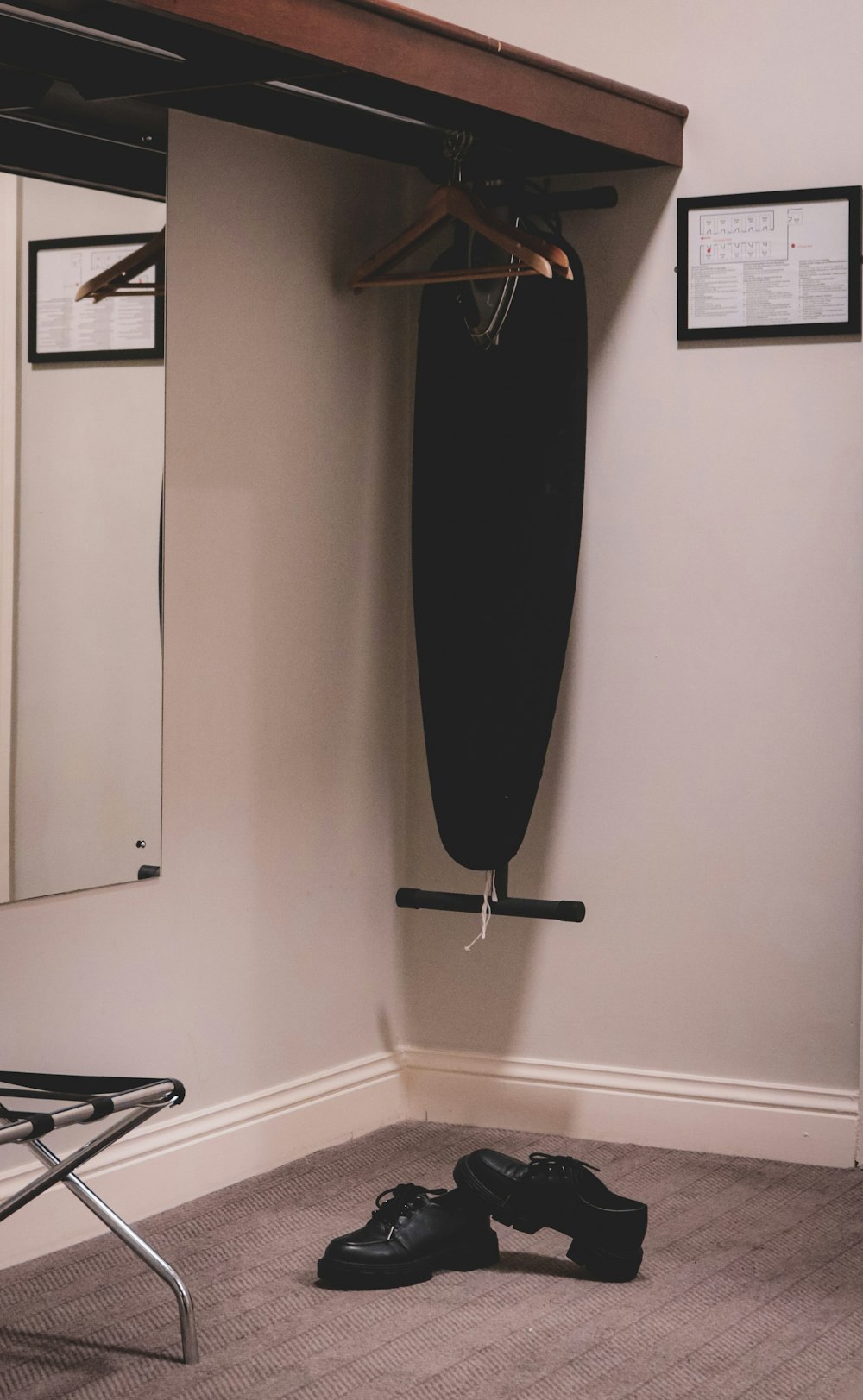 a pair of black shoes sitting under a coat rack