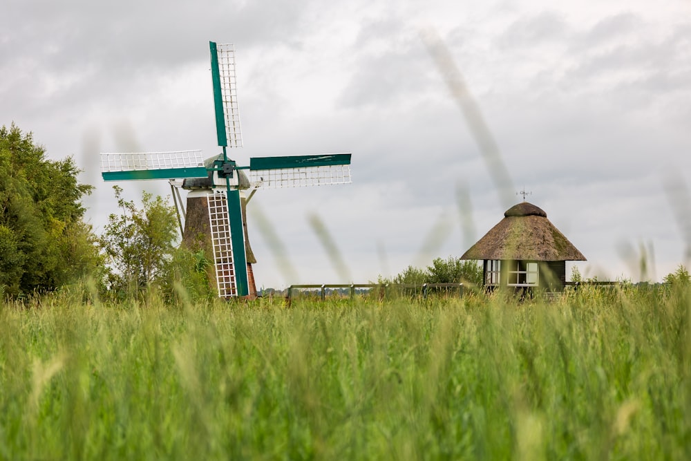 a windmill in a field with a house in the background