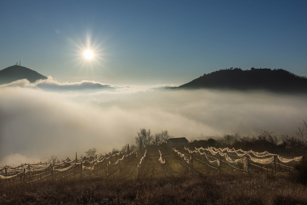 the sun is shining above the clouds in the mountains