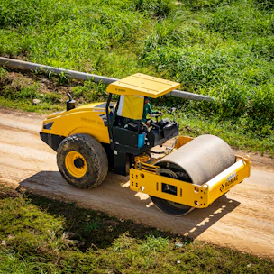 a yellow bulldozer driving down a dirt road