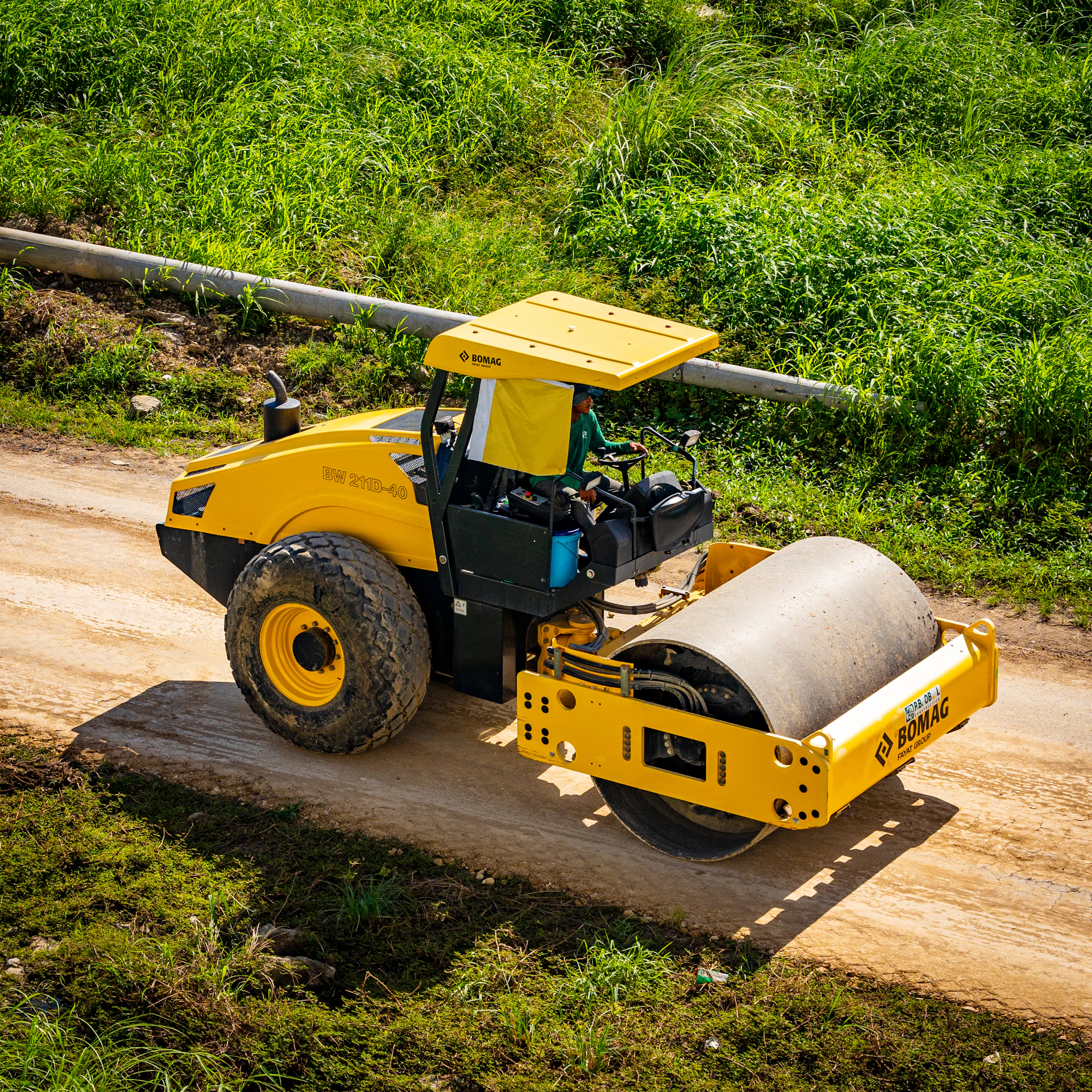 a yellow bulldozer driving down a dirt road