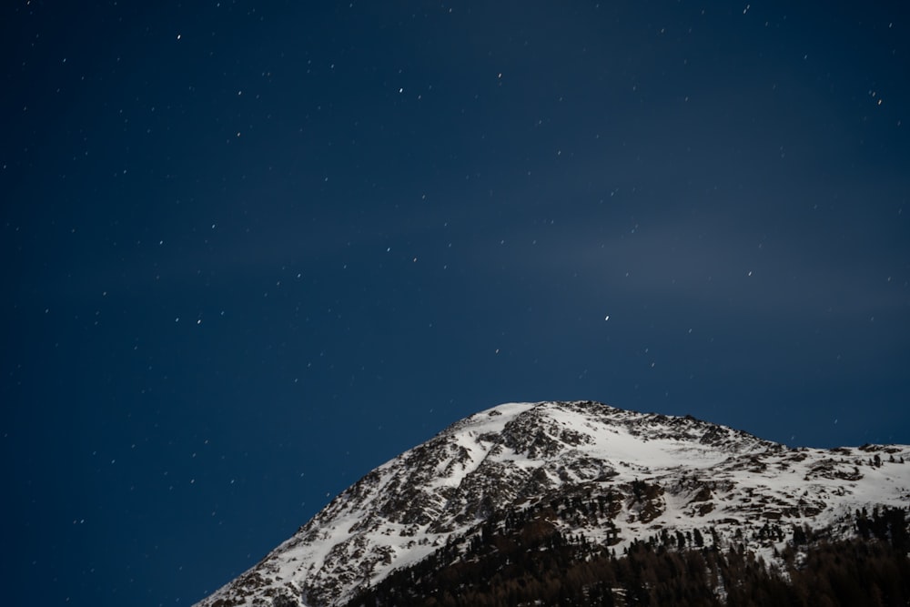 a snow covered mountain under a dark blue sky