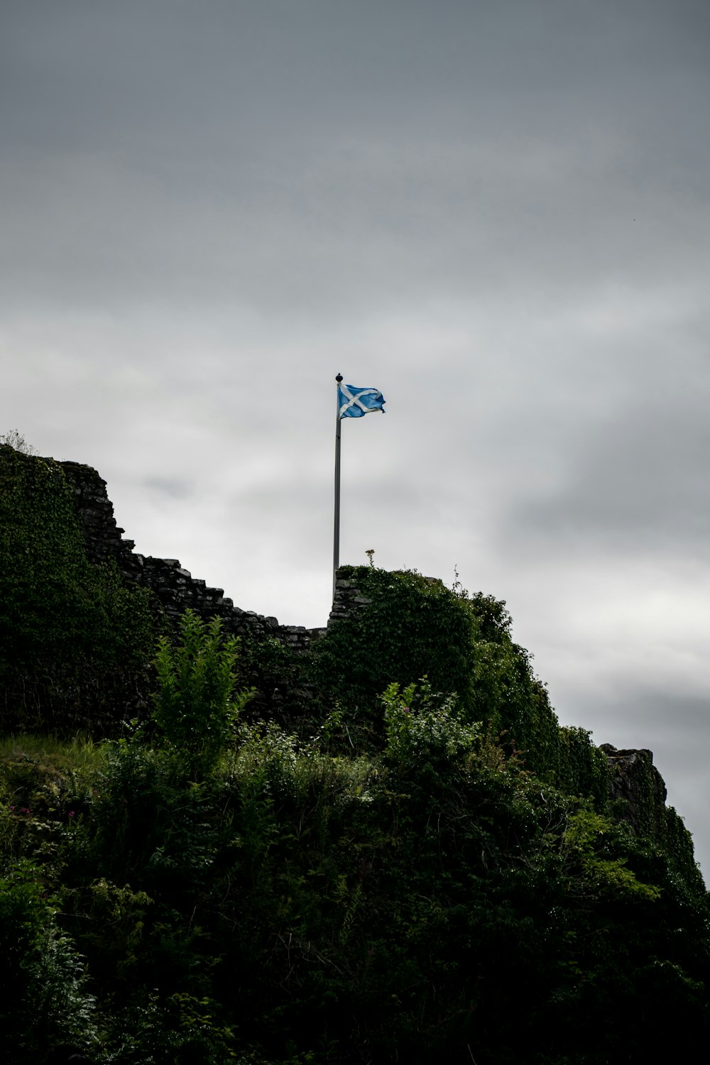 a flag on top of a hill on a cloudy day